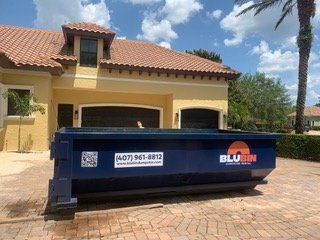 BluBin dumpster on a paver driveway in front of a home
